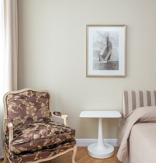 Comfortable armchair with classic design placed in corner of cozy bedroom near bed
