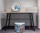 Colorful pouf near table in room