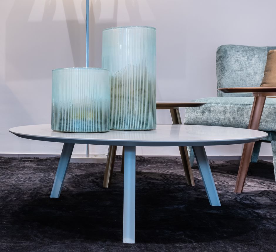 White round coffee table with glass vases in modern living room on carpet near couch