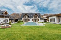 Exterior of contemporary residential cottage house with green lawn in yard under cloudy sky