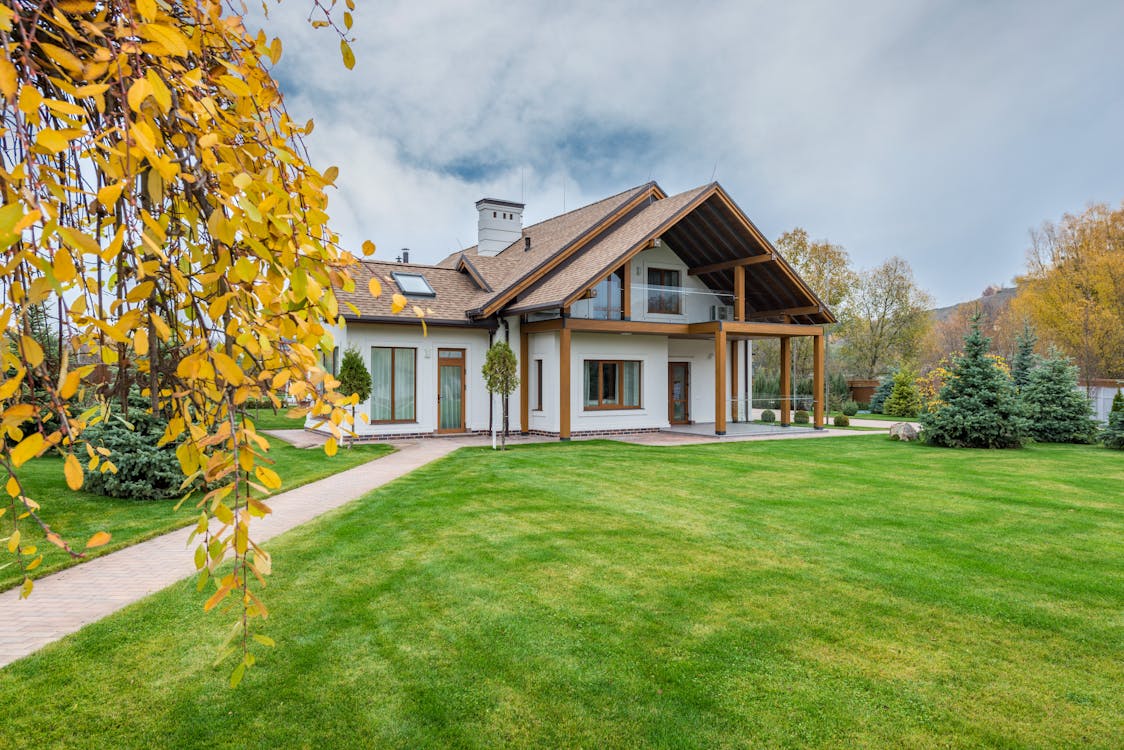 Free Exterior of residential suburban cottage with balcony surrounded with lush green plants and trees Stock Photo