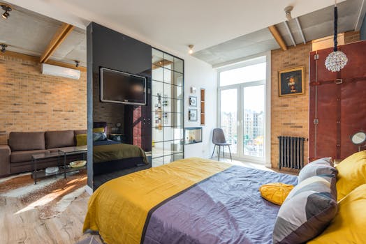 Stylish contemporary bedroom with yellow bedspread and brick walls.