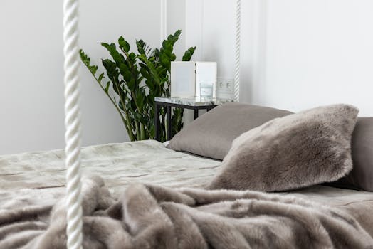 A contemporary bedroom featuring soft textiles and a lush indoor plant, creating a cozy and tranquil atmosphere.