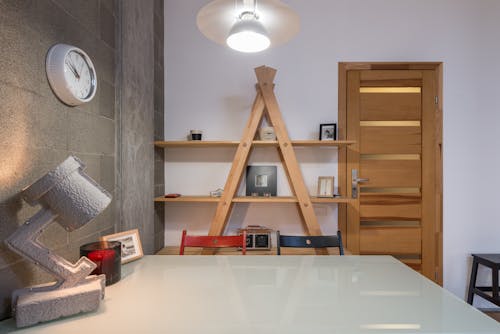 Interior of contemporary room with wooden shelves and big table with colorful chairs in apartment