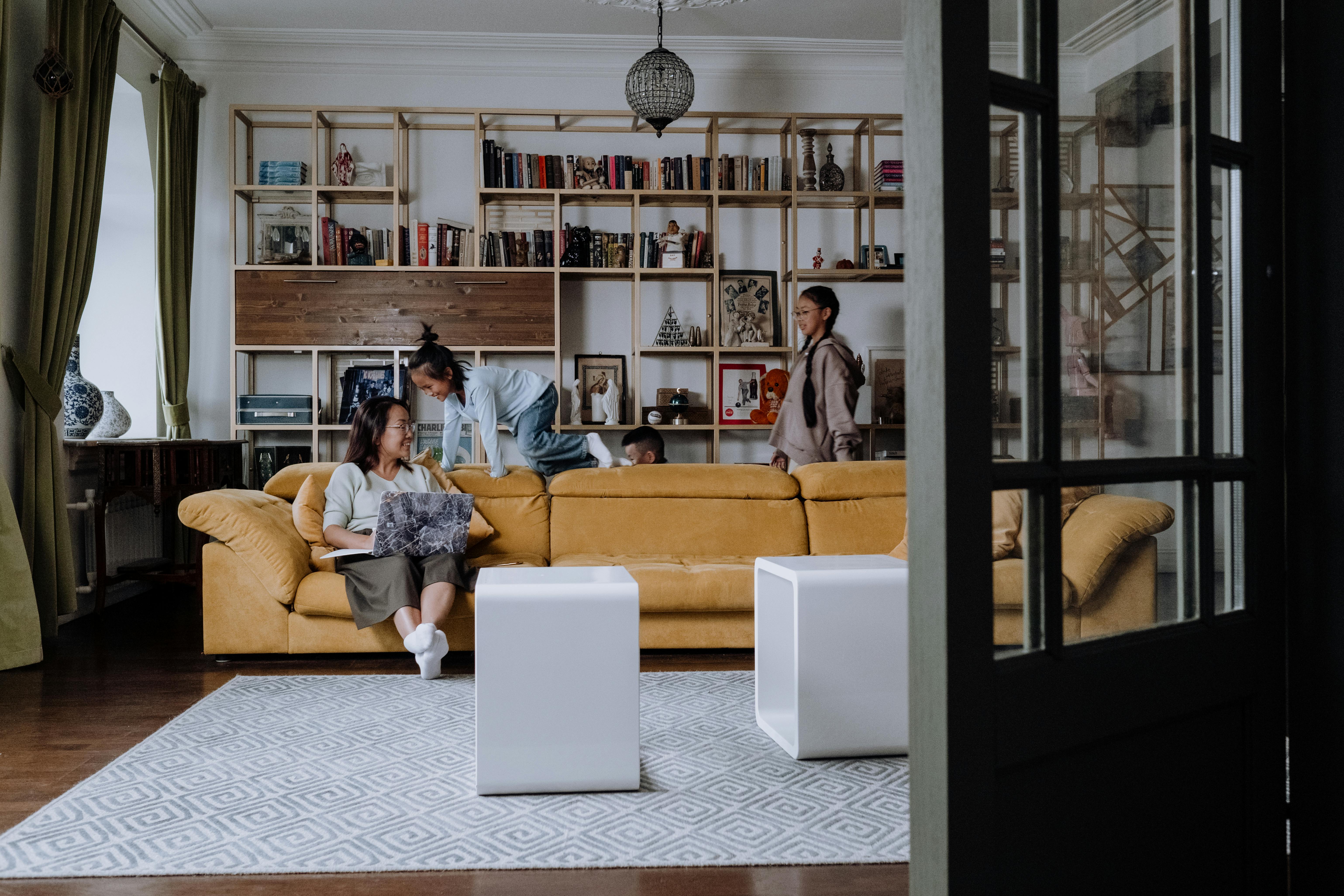 A Woman Sitting on the Couch while Looking at Her Kids