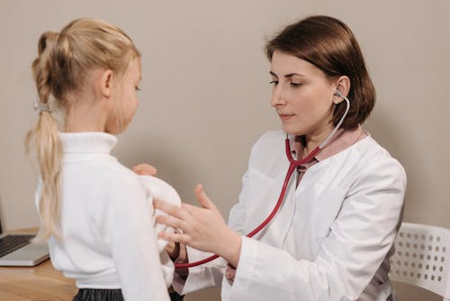 Free Doctor in White Lab Coat Examining Girl's Breath Stock Photo
