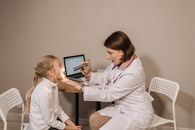 A female doctor examines a child in a clinic setting, ensuring proper medical care and attention.