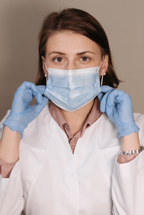 Woman in White Scrub and Blue Latex Gloves Wearing Blue Face Mask