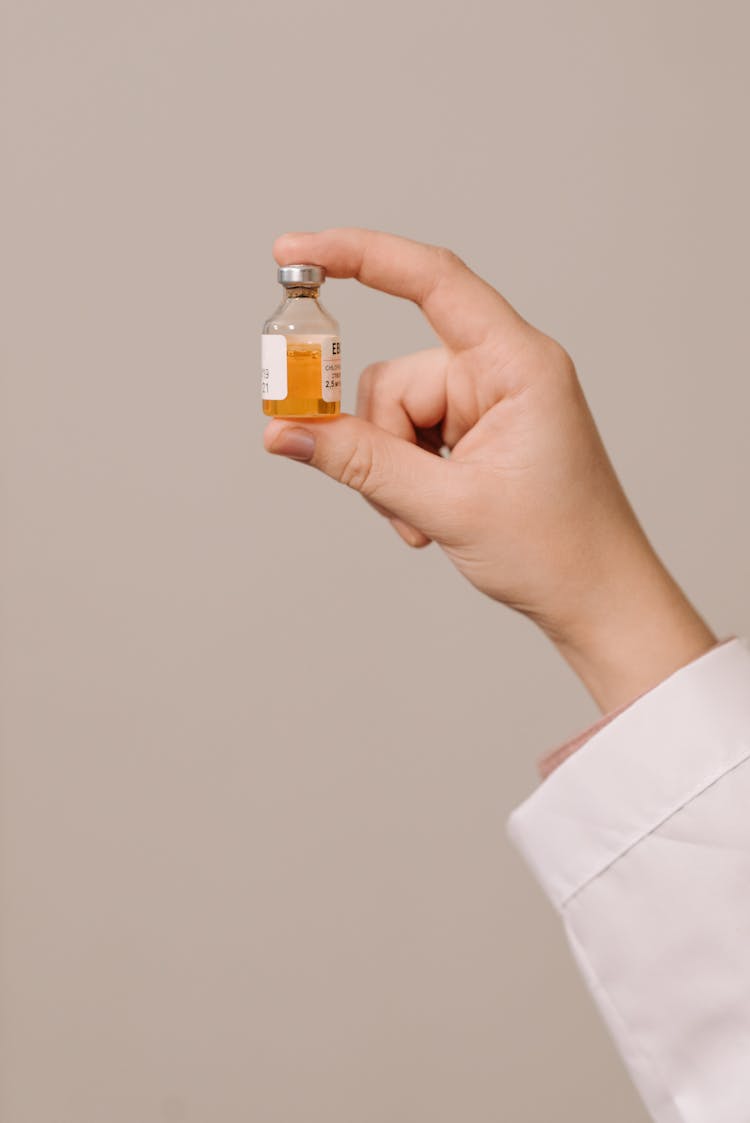 Close-Up Photo Of A Person Holding A Vaccine In A Vial