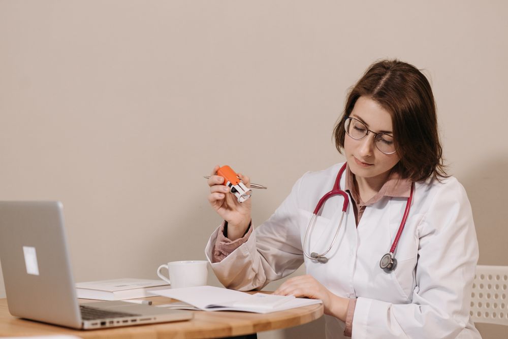 Medical practitioner working with paperwork and laptop in a clinic