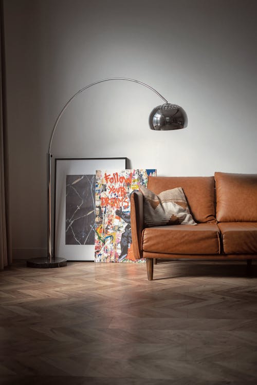 A Silver Floor Lamp near the Paintings and Brown Leather Sofa