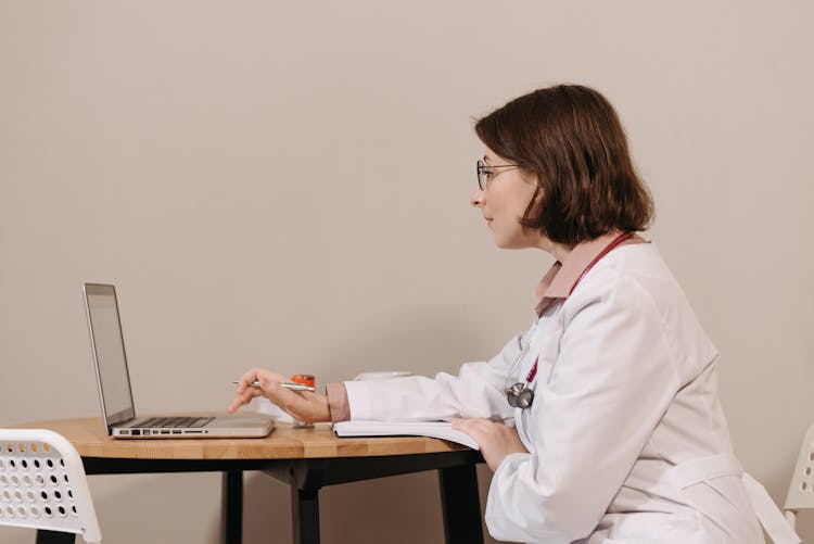 Woman In White Scrub Using Laptop