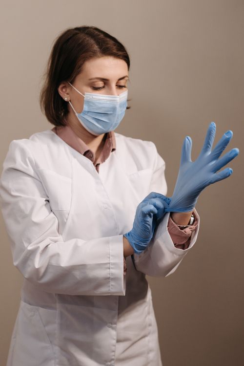 Free Female doctor wearing face mask and gloves, focused on safety. Stock Photo