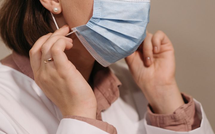 A female healthcare professional adjusting her face mask for safety and hygiene.