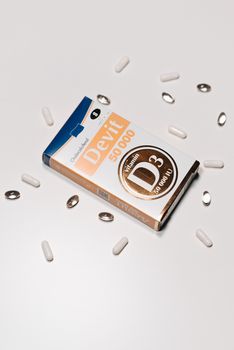 Vitamin D3 50000 IU supplement box surrounded by capsules on a white background.
