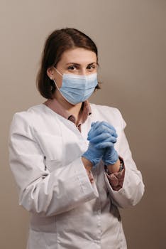 Female healthcare worker wearing PPE, face mask, and gloves in a studio setting.