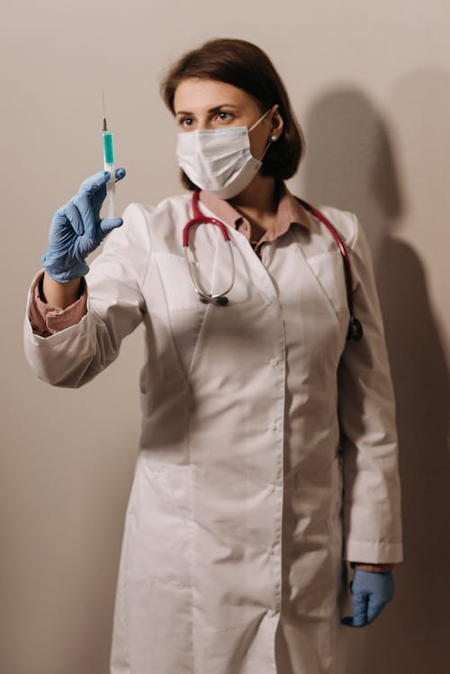 A Physician in White Coat Looking at a Syringe