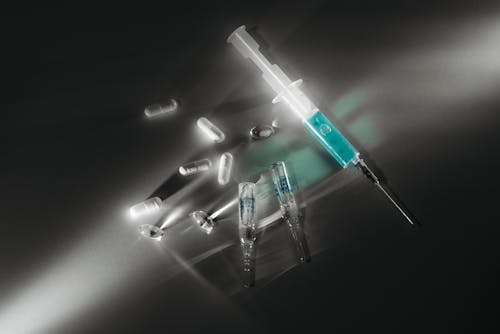Free Syringe and Capsules on White Surface Stock Photo