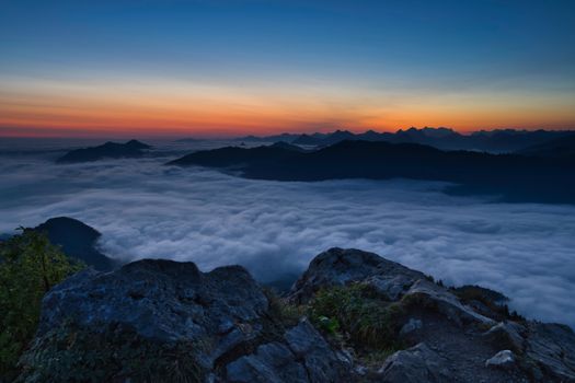 Breathtaking view of sunset above clouds in Bavarian mountains, Germany.