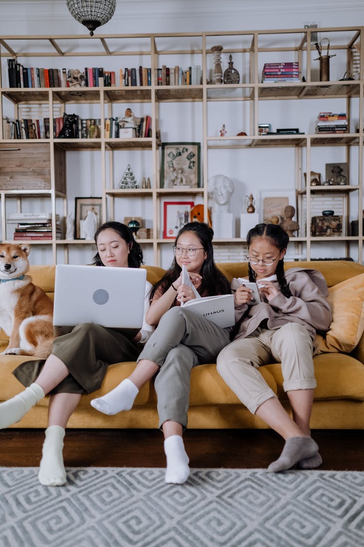 A Mother Sitting On The Couch With Her Daughters