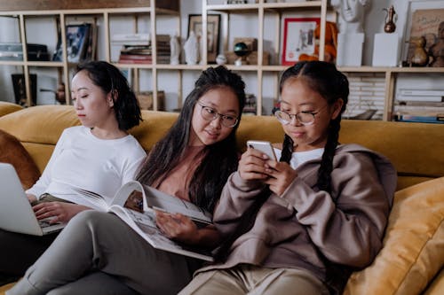 Free Girls Sitting on the Couch while Looking at the Phone Stock Photo