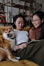 Sisters Sitting on Sofa with their Shiba Inu Dog