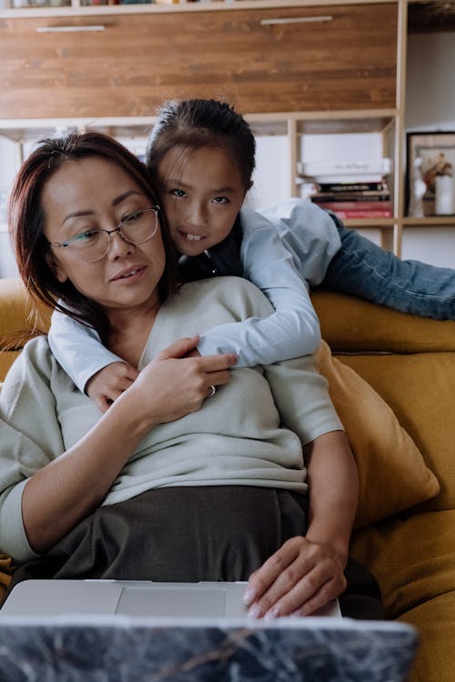 Free A Young Girl Embracing Her Mother while Sitting on the Couch Stock Photo
