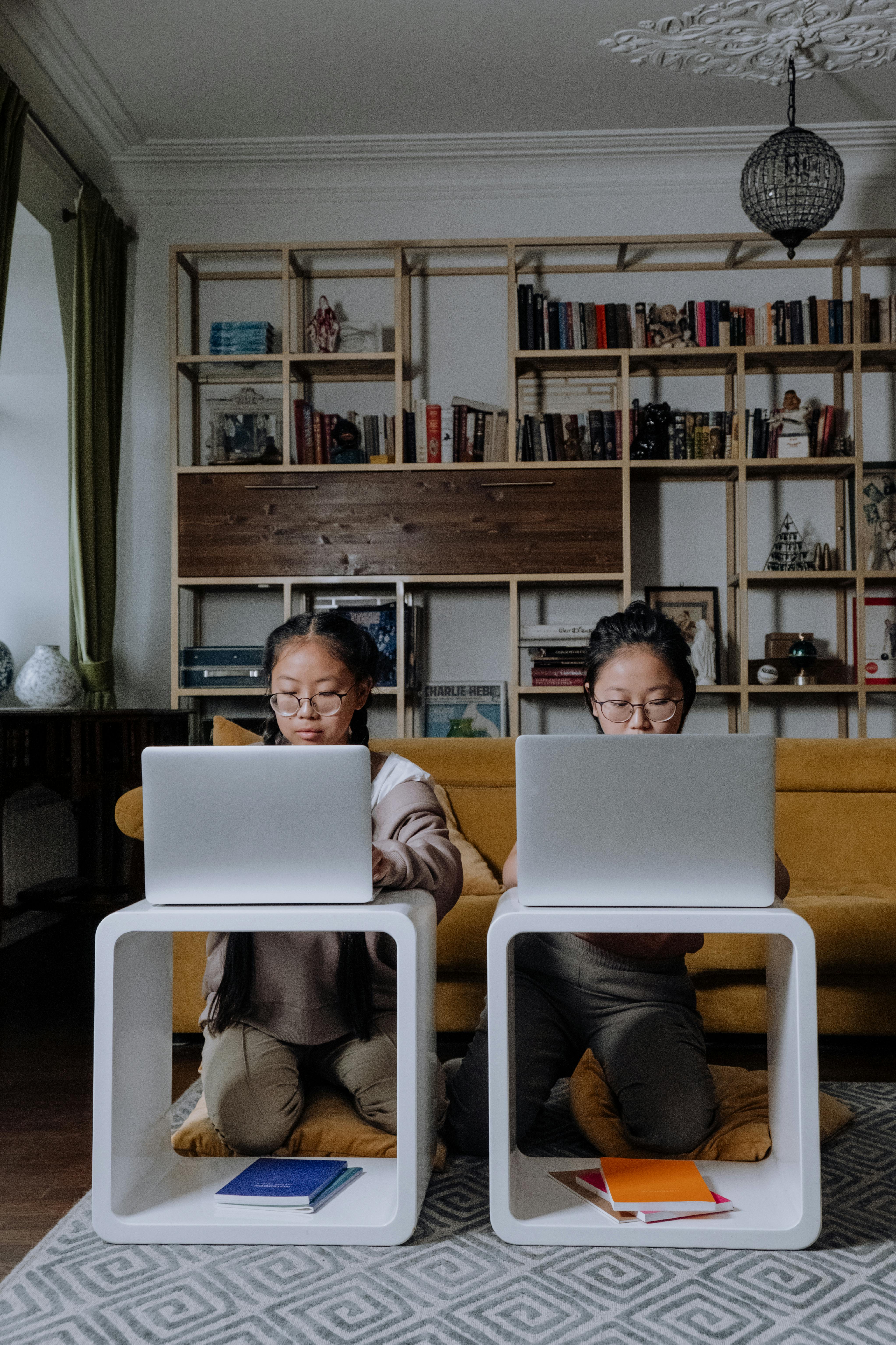 Man in Black Shirt and Gray Pants Sitting on White Chair Using Macbook