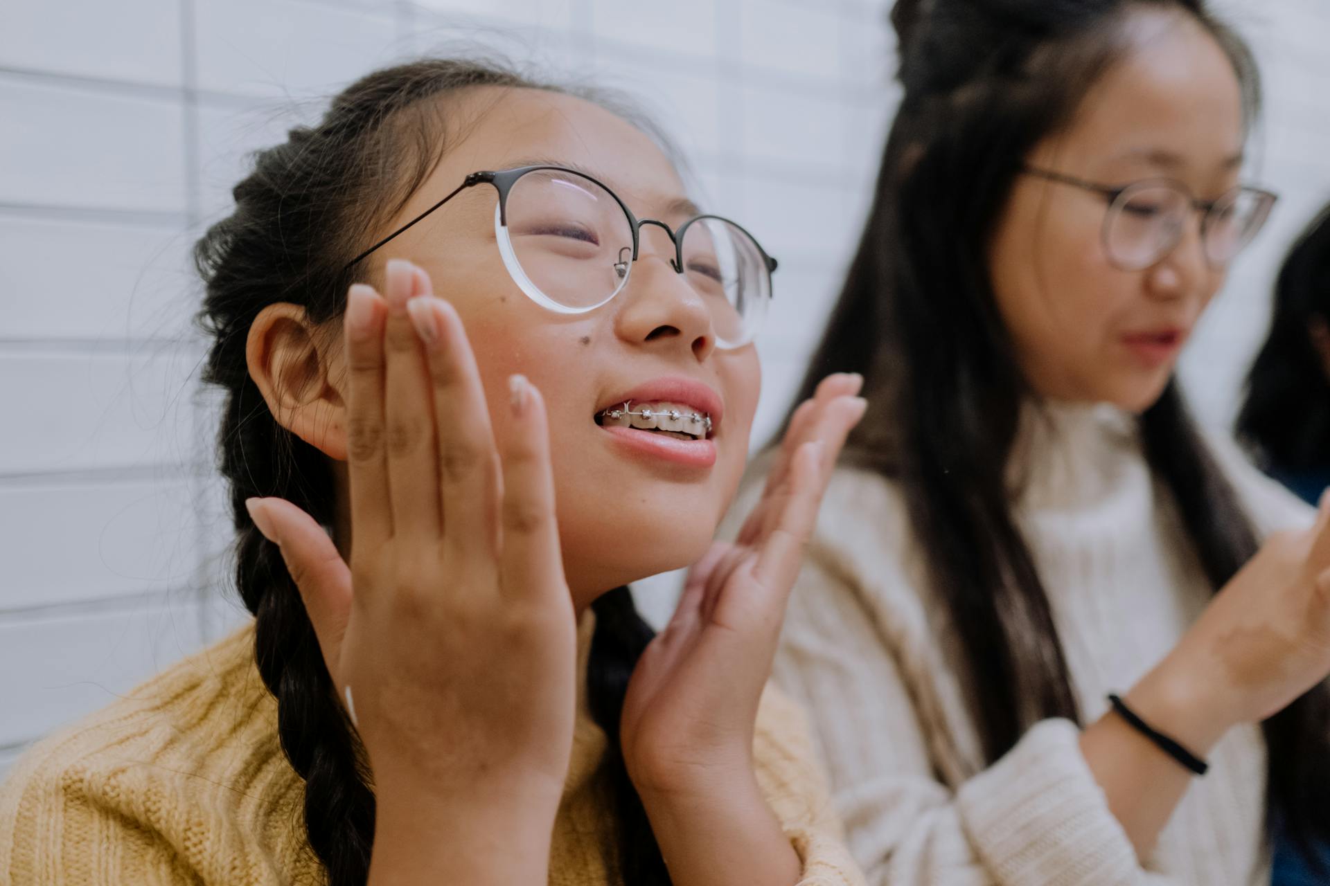 Cheerful teenage girl with glasses and braces smiling indoors, embracing joy and positivity.