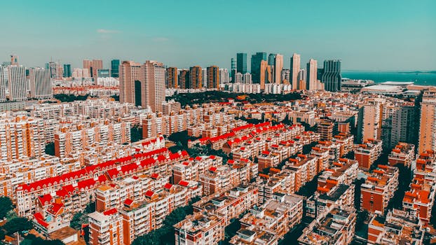 Aerial view of Xiamen's urban skyline featuring vibrant red-topped buildings under a clear sky.