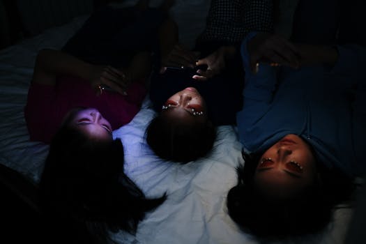 Three young women browsing their smartphones in a dimly lit room, sharing a moment of leisure.