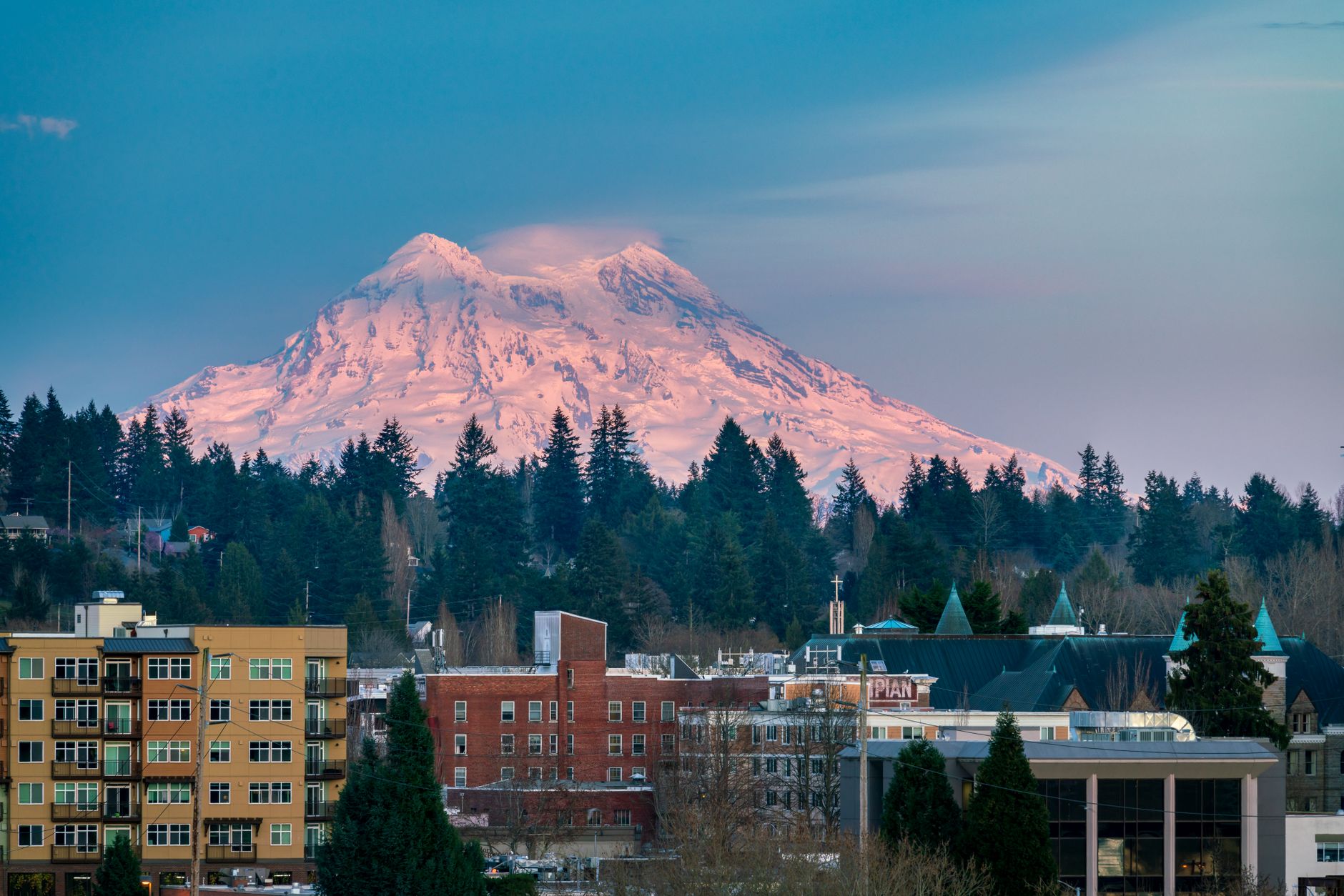 Olympia city skyline with snowcapped Mount Rainier in the background at sunset.