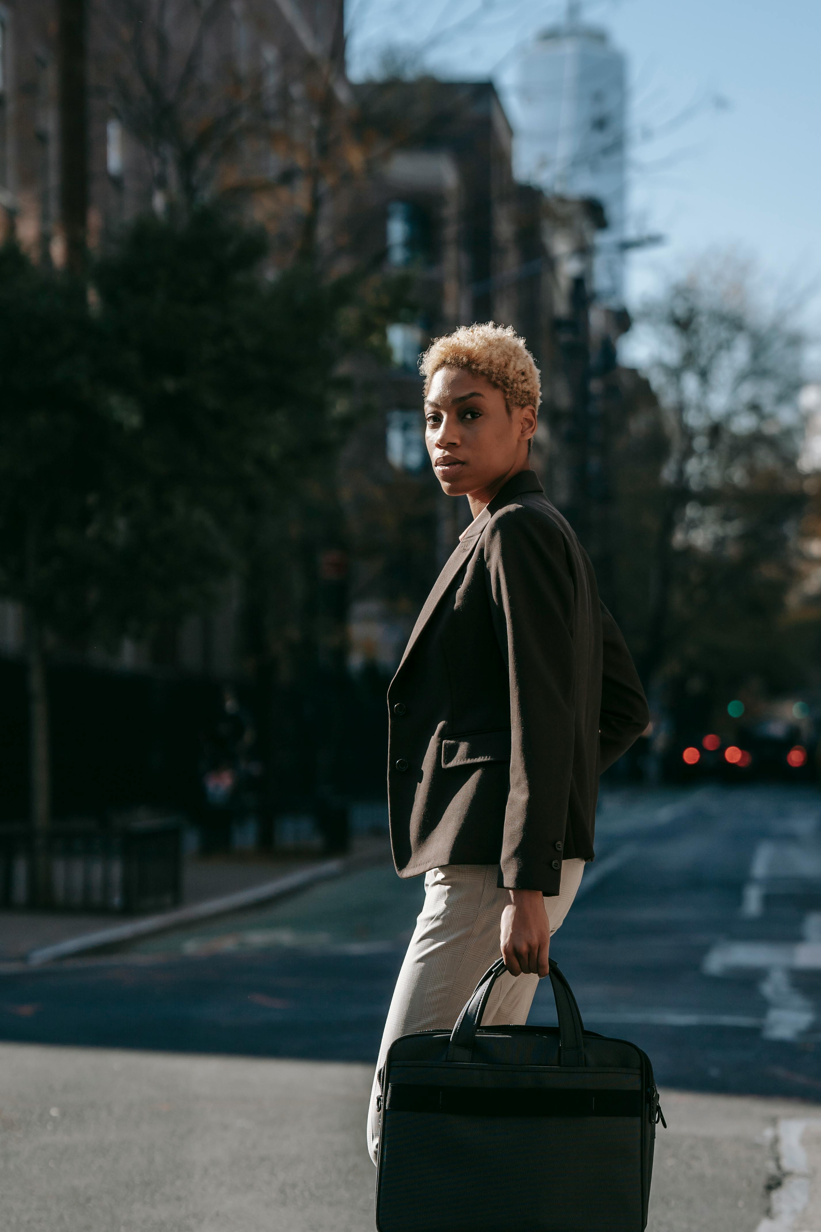 serious young ethnic lady in elegant suit standing on city street