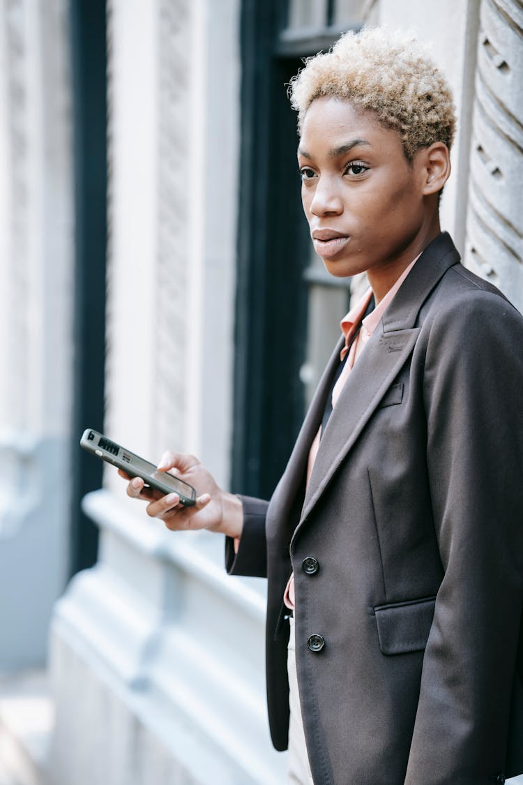 Pensive Ethnic Female Manager Messaging On Smartphone On Street