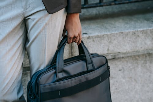 Persona In Camicia Grigia Che Trasporta Borsetta In Pelle Nera