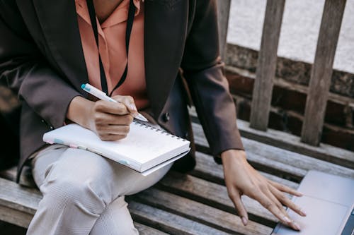 Donna In Giacca Nera E Camicia Di Vestito Bianca Che Tiene Penna E Libro