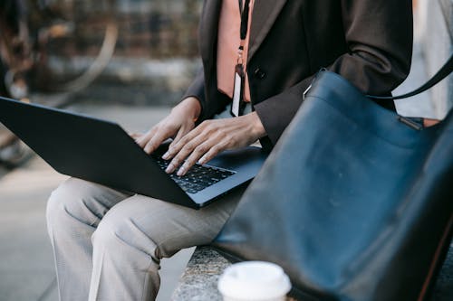 검은 색 노트북 컴퓨터를 사용하는 검은 색 재킷과 흰색 바지를 입은 사람