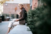 Low angle side view of concentrated African American businesswoman touching chin with pen while attentively looking away