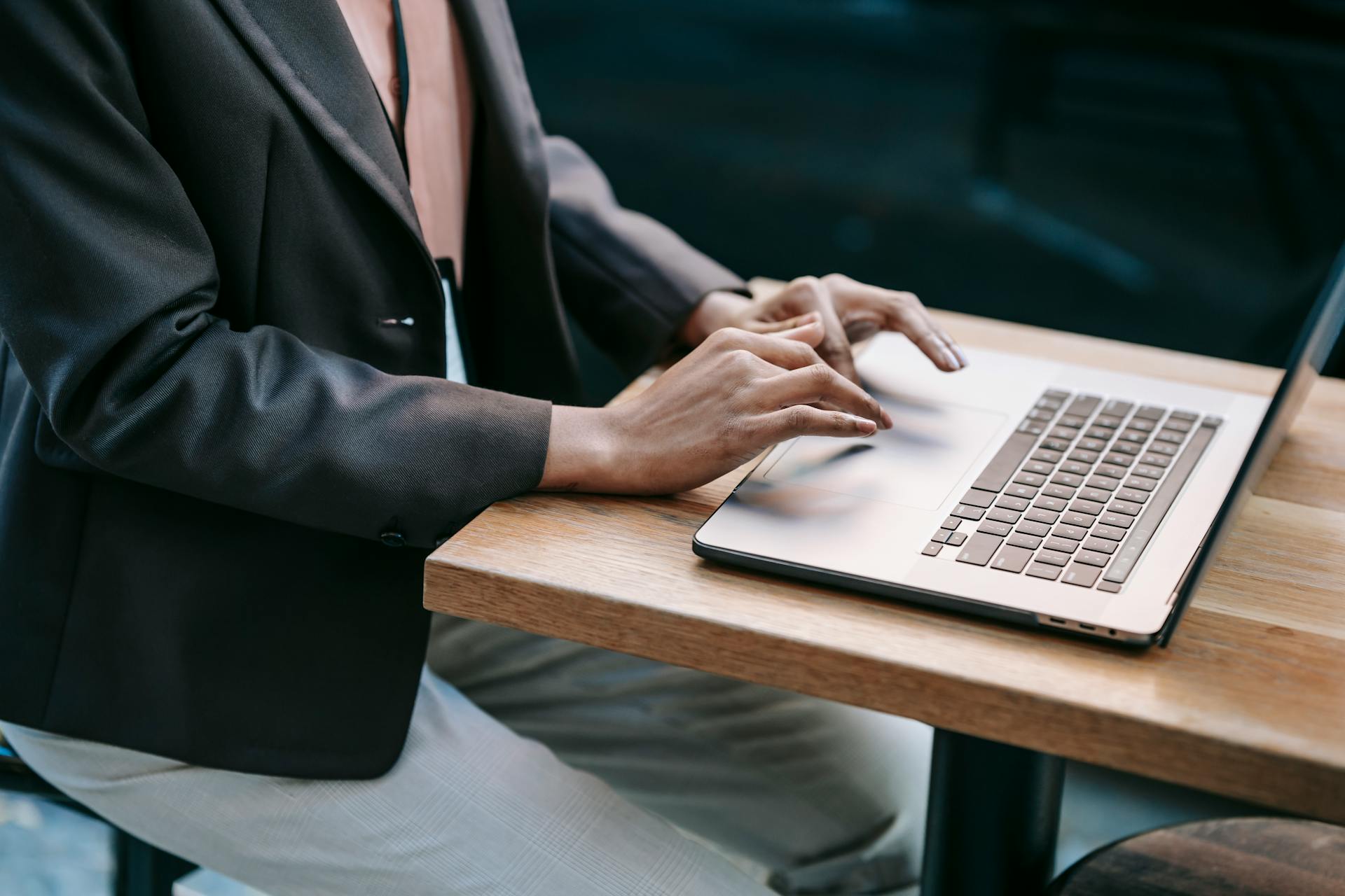 High angle side view of crop anonymous ethnic entrepreneur wearing formal outfit surfing netbook during work in cafe