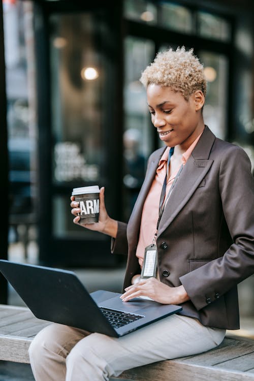 Smiling black businesswoman using laptop and drinking coffee