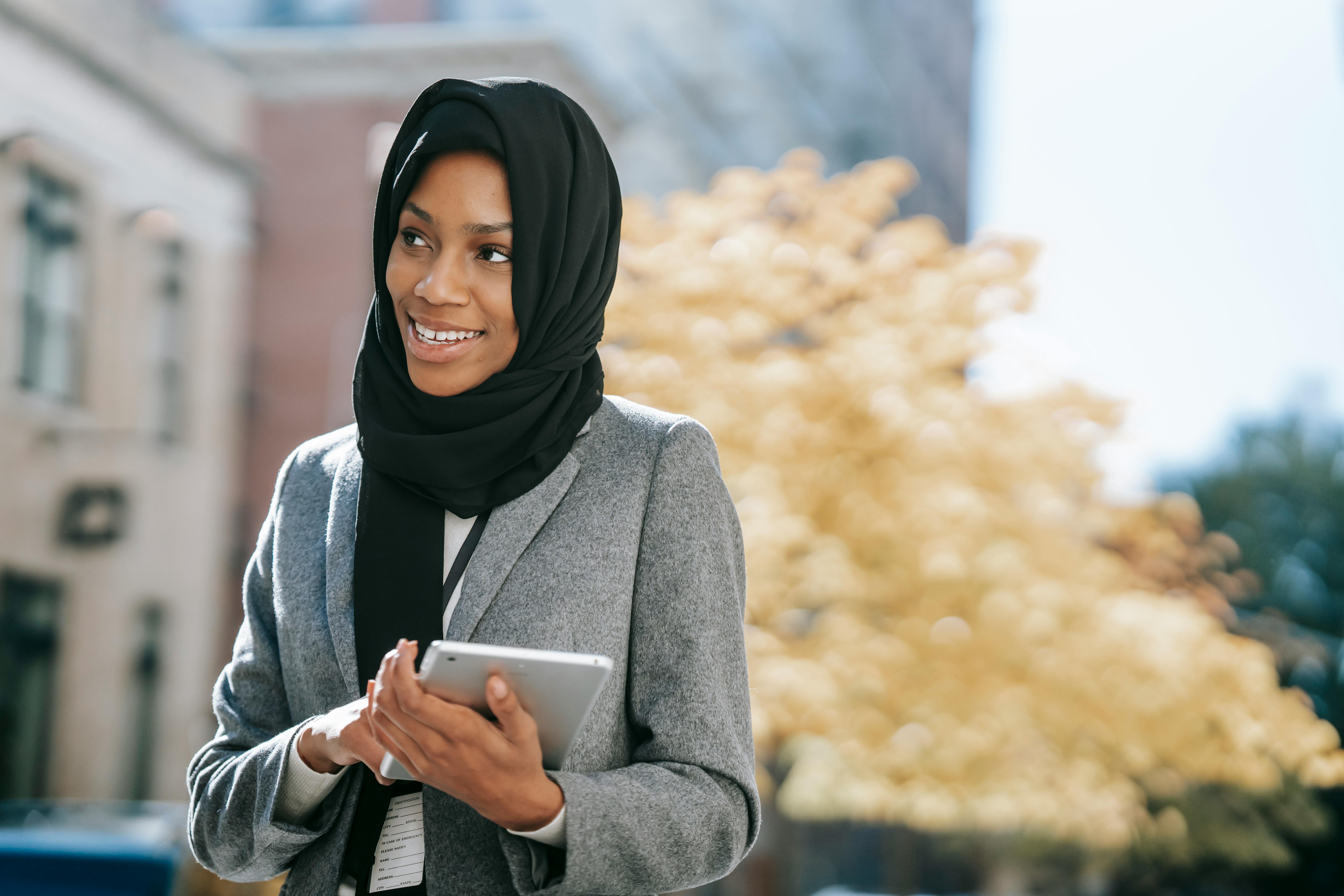 glad ethnic office worker with tablet in town