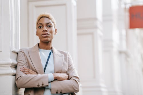 Free Young self assured African American female entrepreneur with folded arms looking forward near building column in city Stock Photo