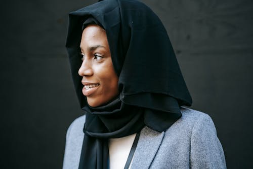 Crop smiling black manager in headscarf in daytime
