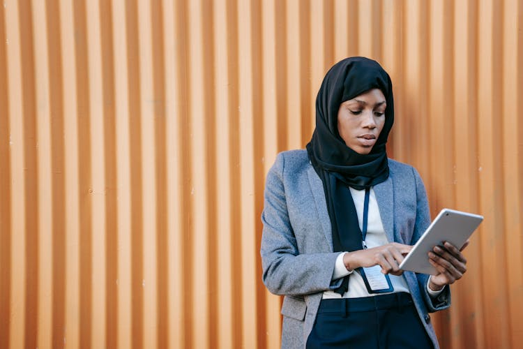 Serious Black Manager Watching Tablet Near Ribbed Wall