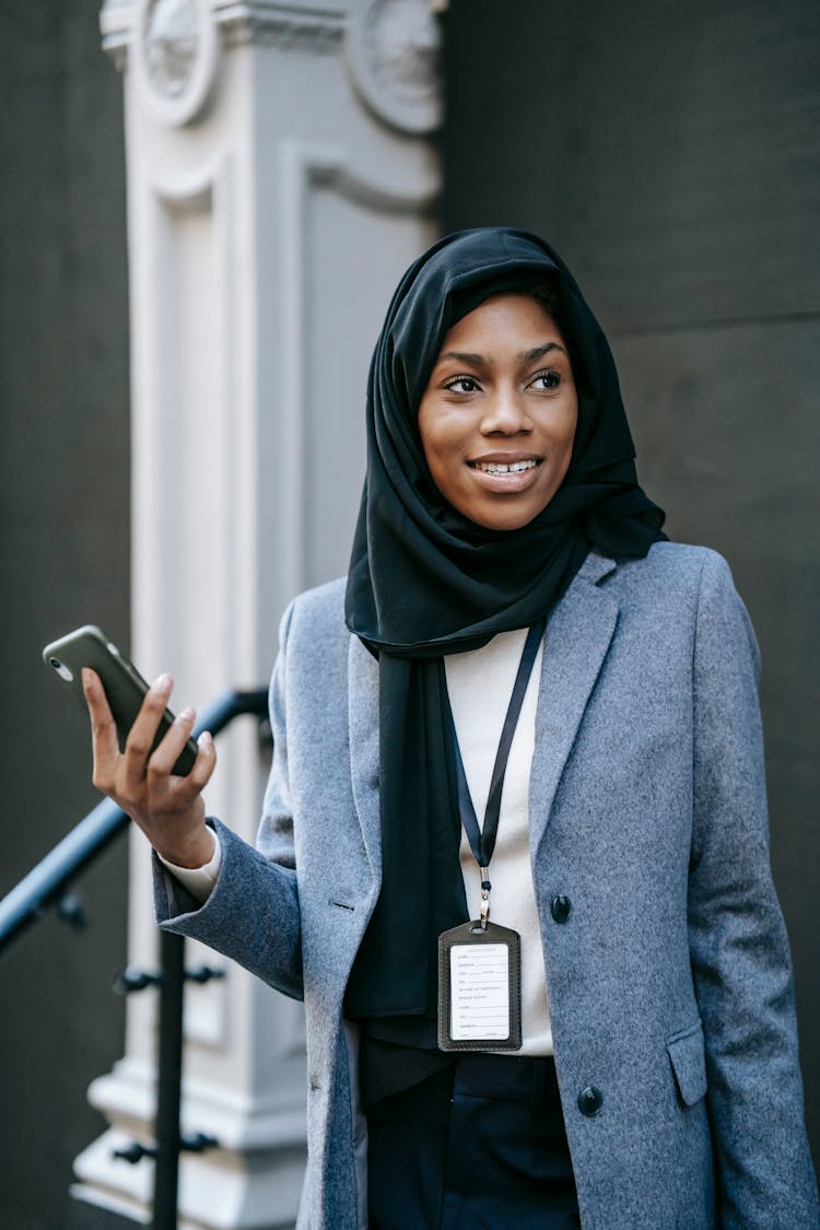 Smiling Ethnic Office Worker With Smartphone On Street