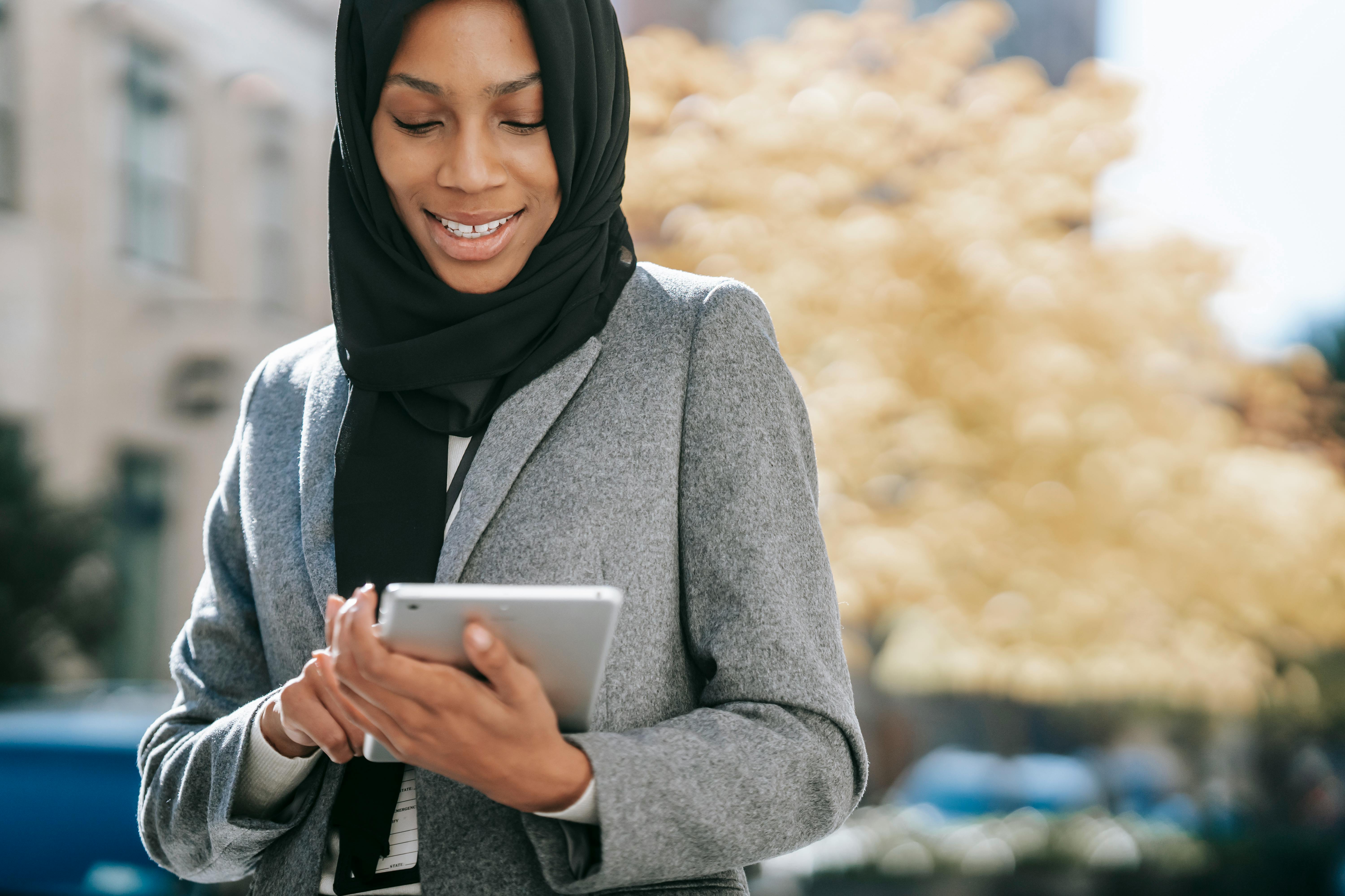 positive muslim businesswoman using table on street