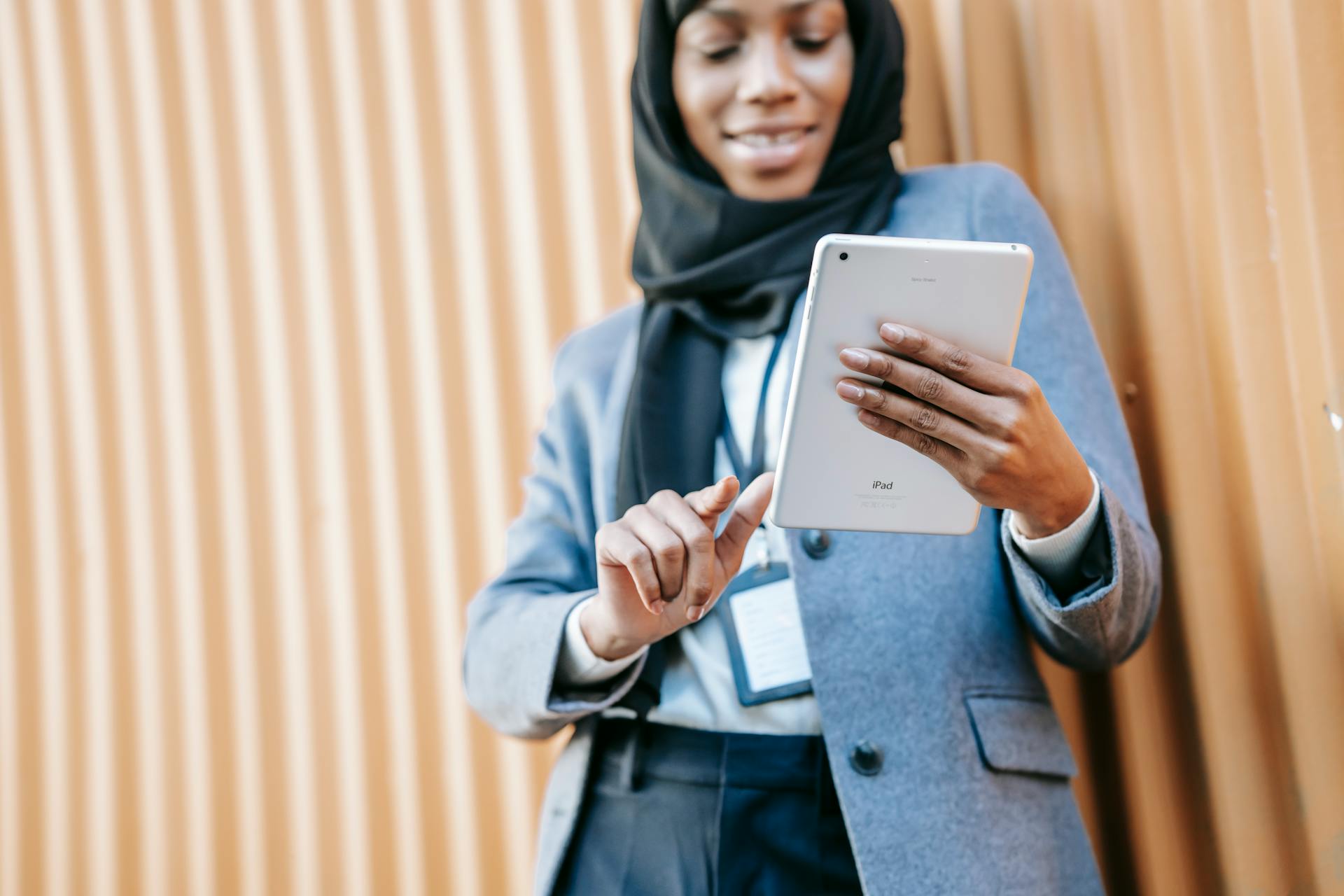 Elegant Muslim woman in hijab uses a tablet for online work outdoors. Professional and connected.