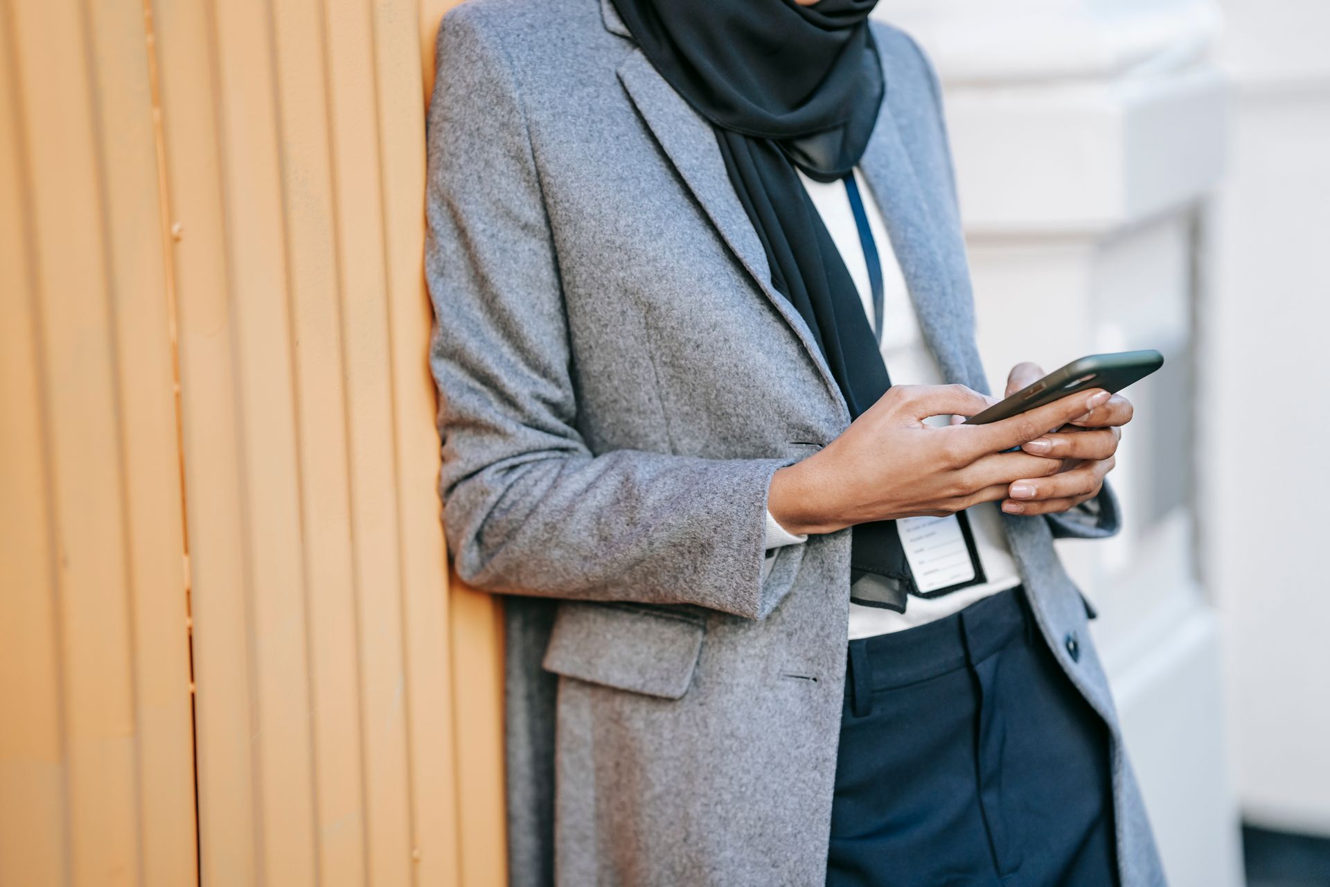 Businesswoman in smart attire using smartphone outdoors, symbolizing communication and technology.