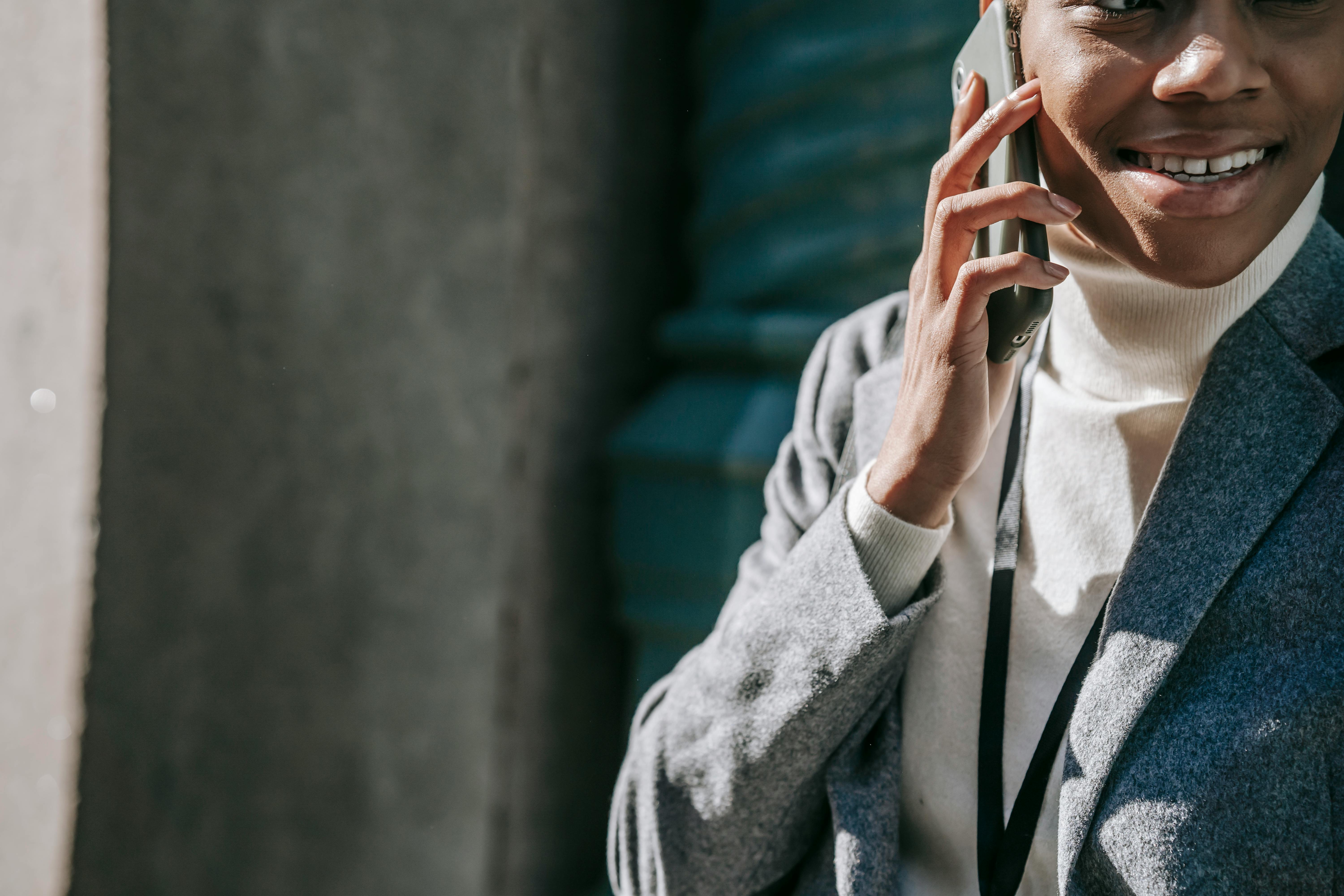 happy young black woman talking on phone and smiling in sunlight