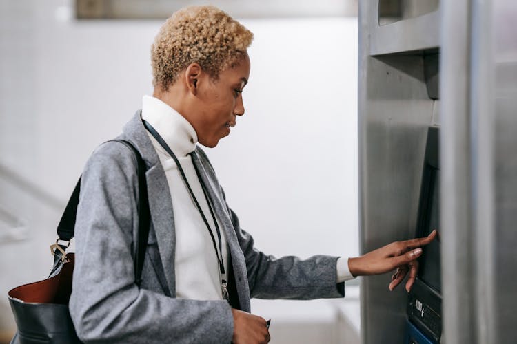 Young African American Woman Touching Screen Of Ticket Machine In Metro Station